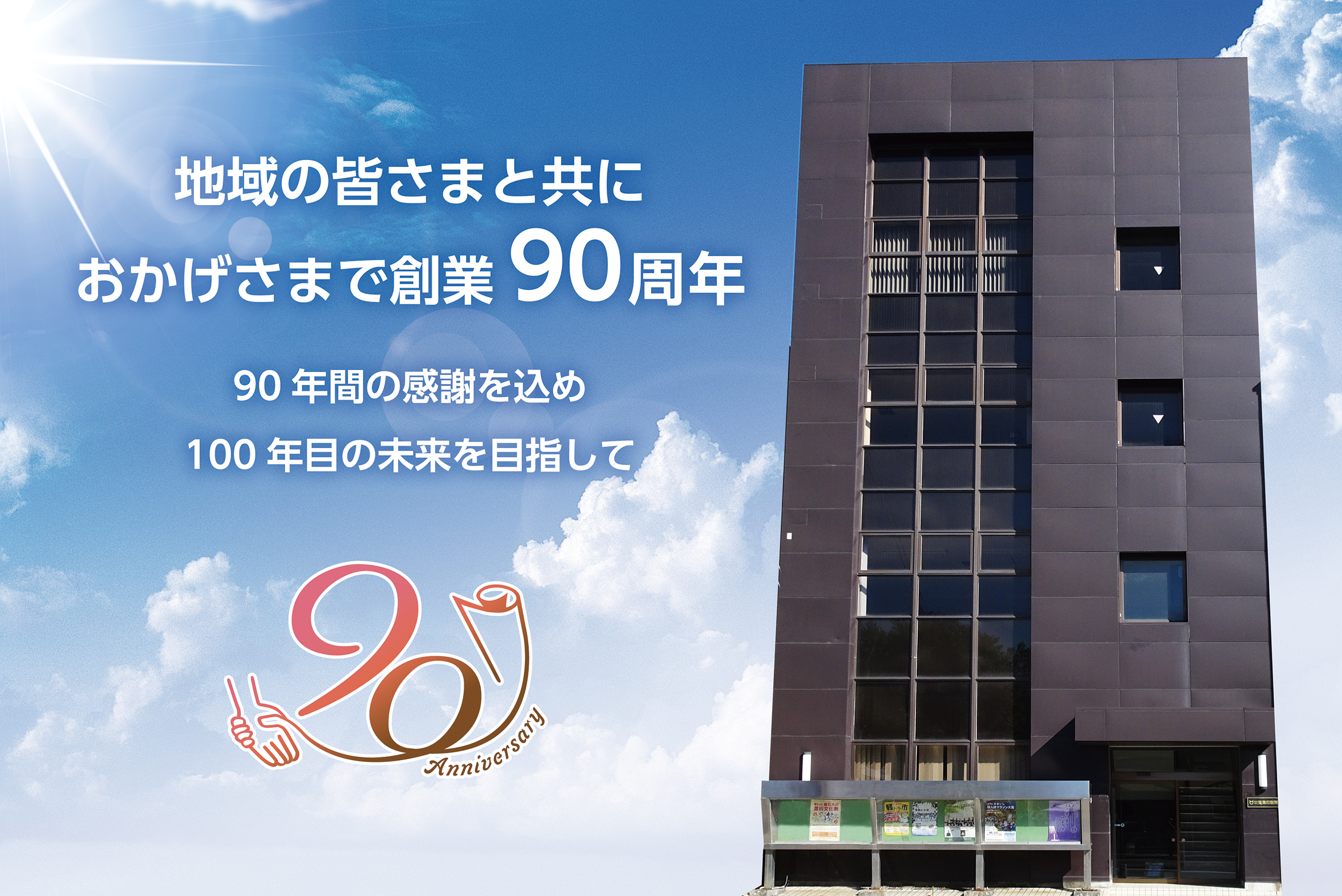 青空を背景にした社屋 地域の皆さまと共におかげさまで創業90周年